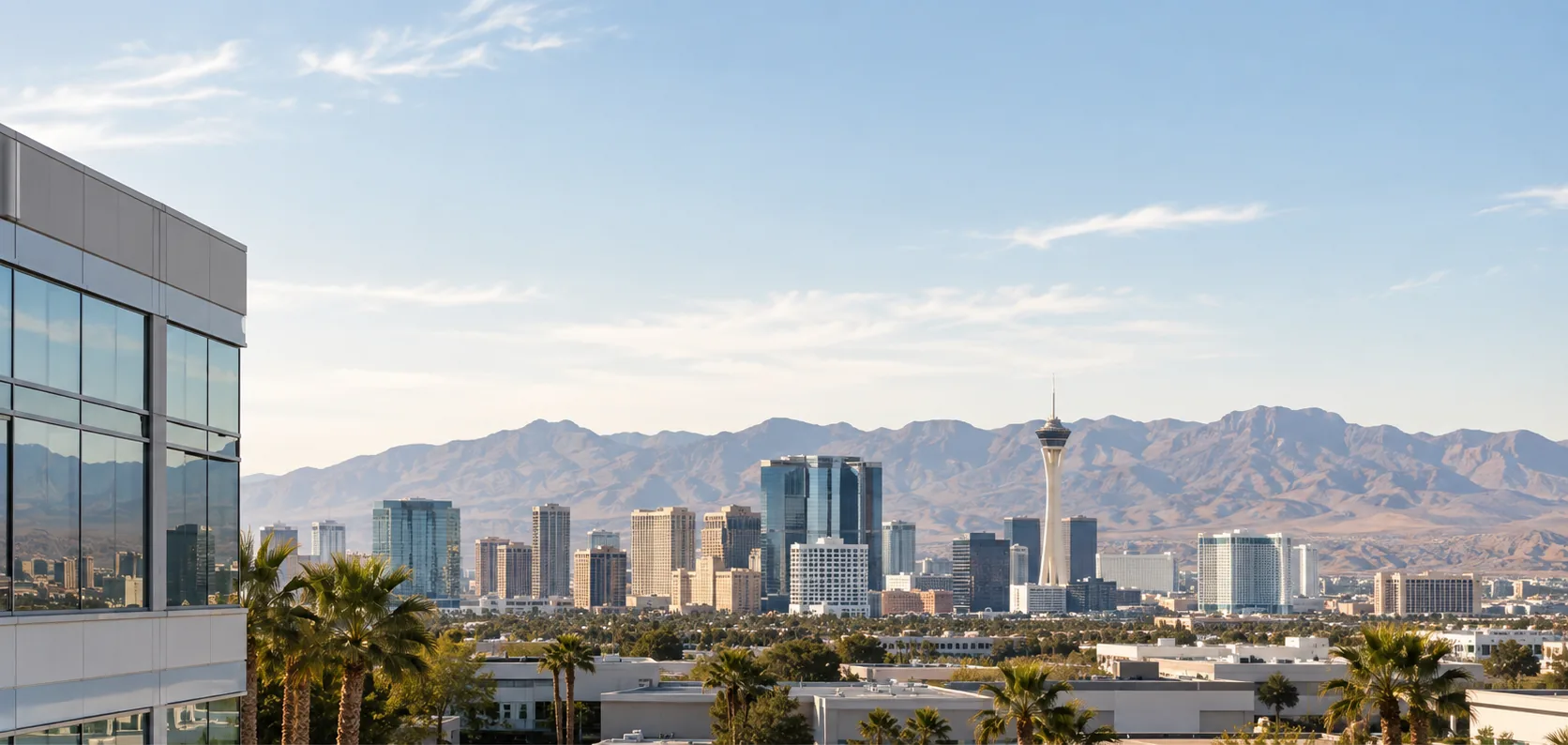 Daylight view across the Las Vegas valley, office towers in the middle distance with the desert mountain range behind them.